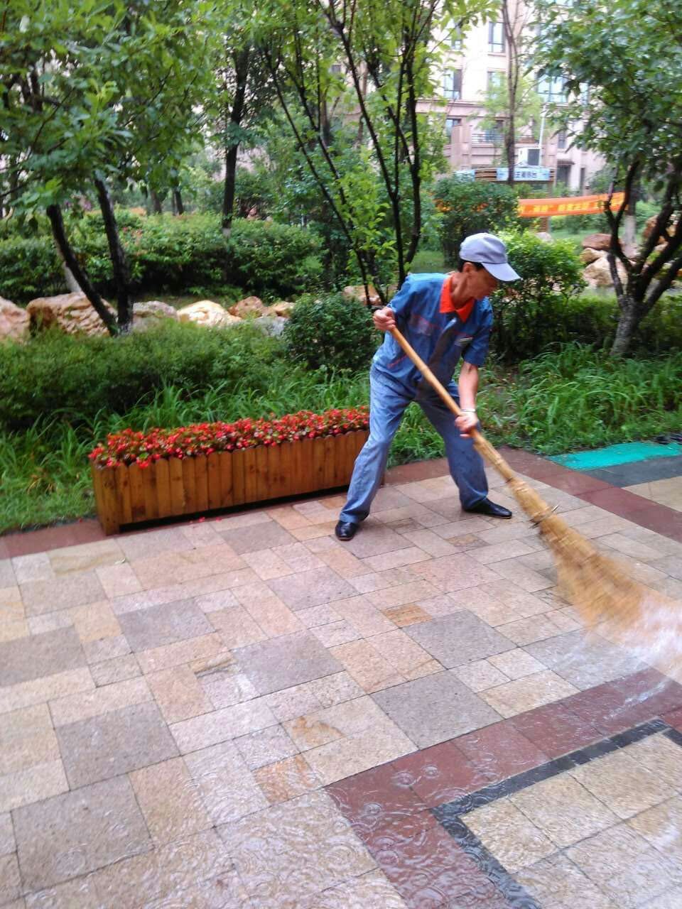 雨还没完全停,保洁员已经开始清扫积水